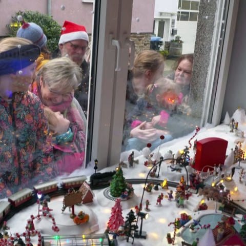 Kinder bestaunen Mini-Winter-Wunderland im Küchenfenster