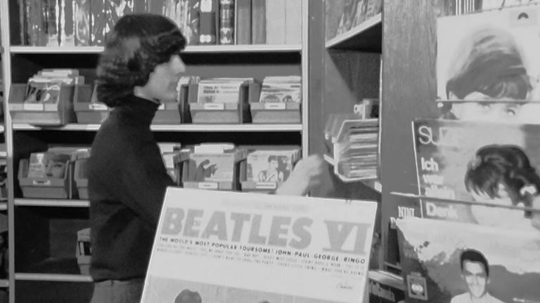 Der 15-jährige Thomas zieht eine Schallplatte der Beatles aus dem Regal, er trägt auch eine Frisur nach ihrem Vorbild.