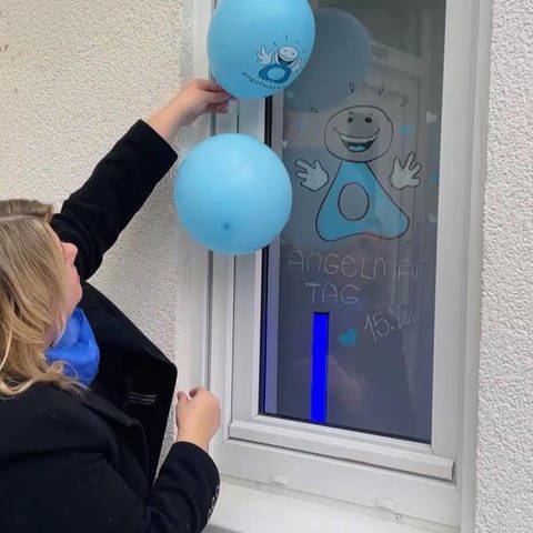 Frau hängt blaue Luftballons auf