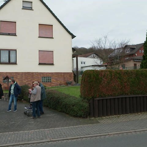 Anwohner stehen vor einem Haus