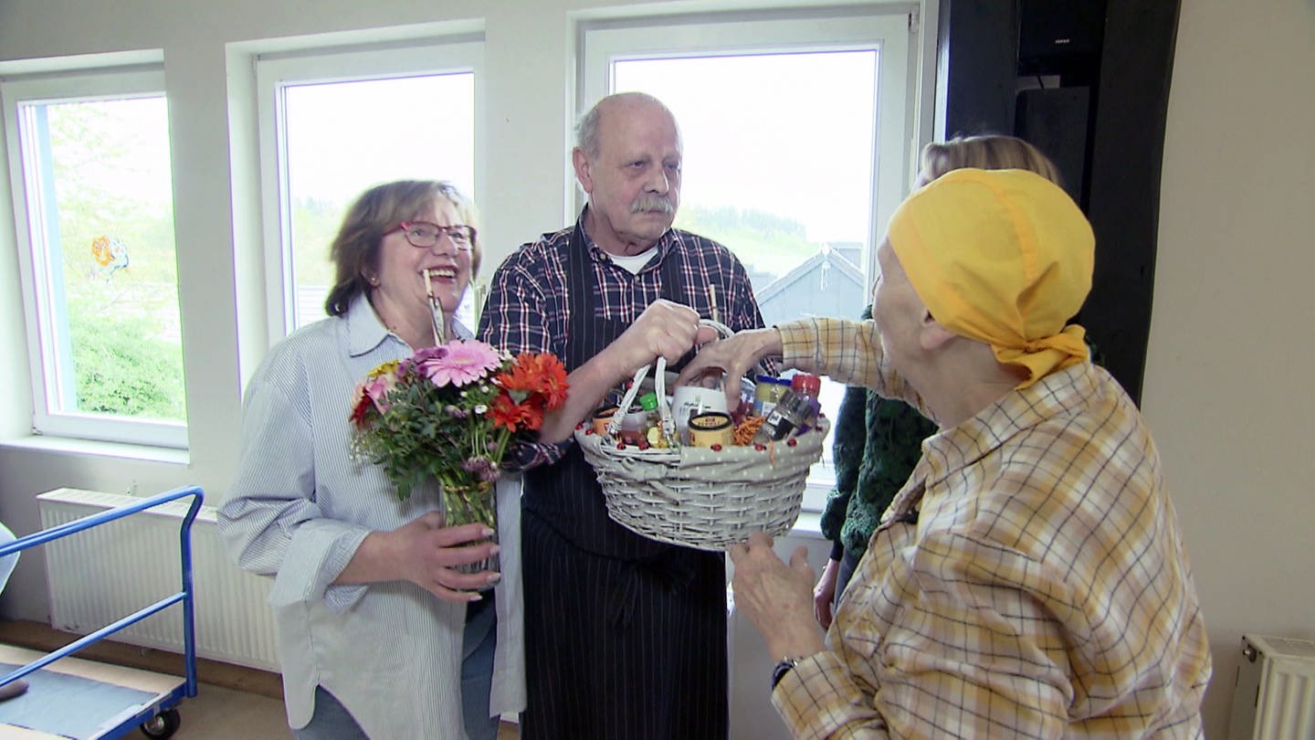 Marina van Asch (r,) bedankt sich bei Brigitte und Jürgen Schäfer mit Blumen und einem Geschenkkorb. (Foto: SWR)