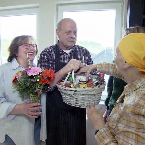 Marina van Asch (r,) bedankt sich bei Brigitte und Jürgen Schäfer mit Blumen und einem Geschenkkorb. (Foto: SWR)