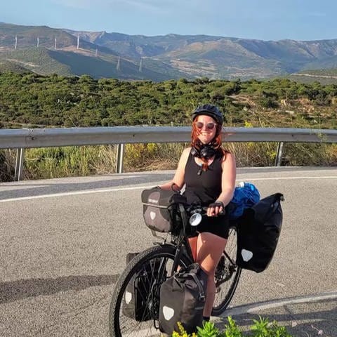 Johanna Rothmann auf dem Fahrrad vor einer Bergkulisse