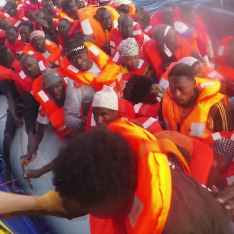 Schlauchboot voller Flüchtlinge wird von Rettungsschiff längsseite genommen. Flüchtling wird an Bord geholt (Foto: SWR)