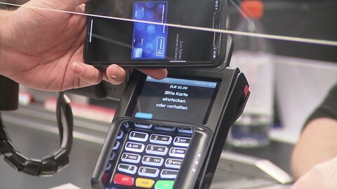 Anonyme Hand hält Smartphone an Kartenlesegerät an Supermarktkasse (Foto: SWR, SWR)