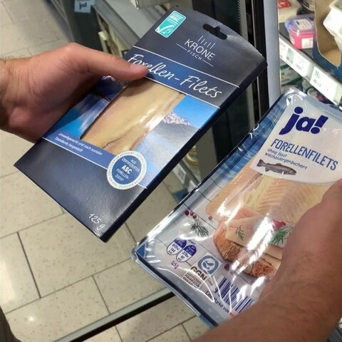 Anonyme Hand hält zwei Packungen mit Forellenfiltes vor sich: Einmal das Markenprodukt Krone, einmal die Rewe-Eigenmarke  (Foto: SWR)
