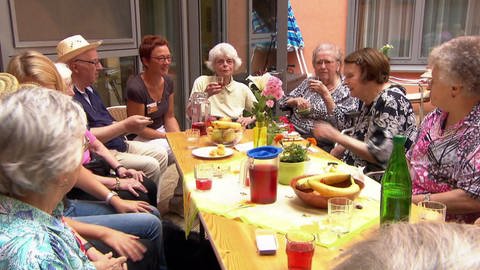 Senioren trinken, an einem Gartentisch sitzend. (Foto: SWR)