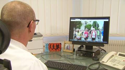 Mediziner sitzt vor einem Bildschirm und sieht eine Bildsequenz mit Marathonläufern (Foto: SWR)
