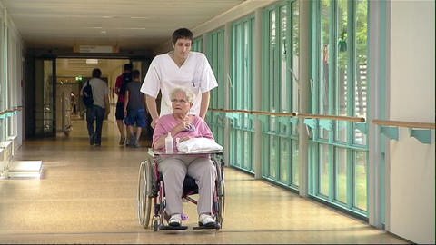 Kranken- und Alten-Pflege: Freiwilliger Helfer schiebt Rollstuhl (Foto: SWR)