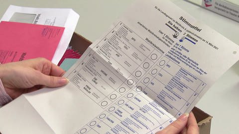 Frau hält entfalteten Stimmzettel der Briefwahlunterlagen in den Händen (Foto: SWR)