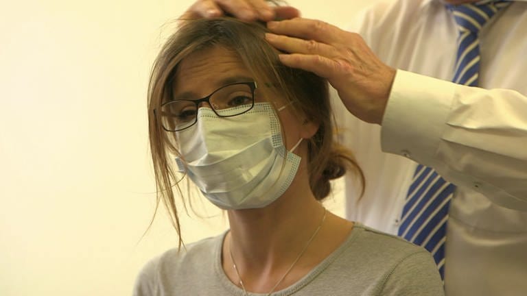 Eine Frau mit Kopfschmerzen beim Arzt