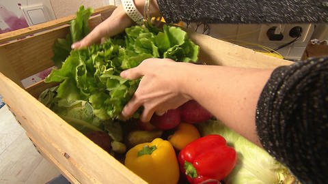 Frau greift in eine Holzkiste mit frischem Gemüse und einem großen Salatkopf (Foto: SWR)