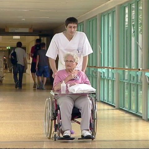 Kranken- und Alten-Pflege: Freiwilliger Helfer schiebt Rollstuhl