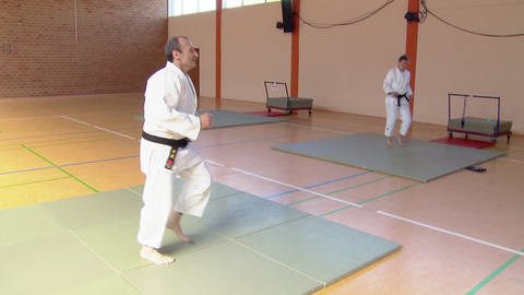 Zwei Judoka trainieren Synchronbewegungen auf Distanz in einer Sporthalle (Foto: SWR)