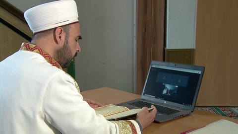 Imam sitzt vor Laptop und kommuniziert mit seinen Gläugigen online. (Foto: SWR)