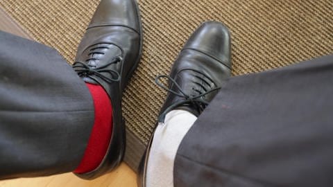 Mann trägt zwei unterschiedliche Socken in Anzugschuhen
