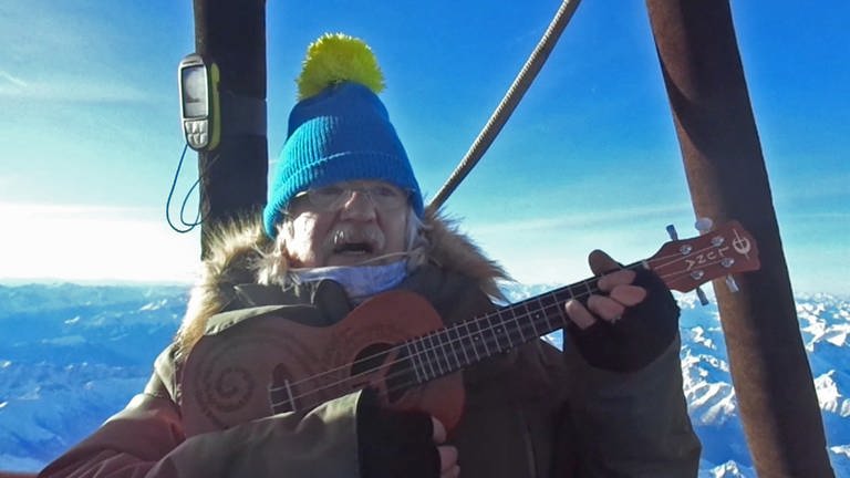 Liedermacher und Friedensaktivist Uli Valnion spielt Gitarre in einer Berggondel (Foto: SWR)