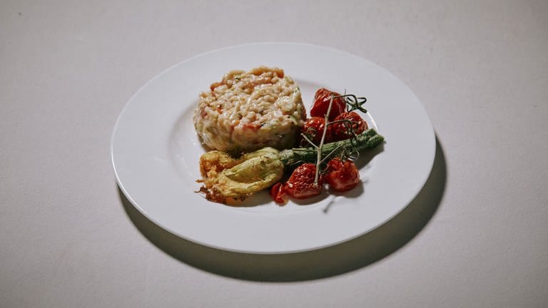 Tomaten-Zucchini-Risotto mit Beilagen auf einem Teller