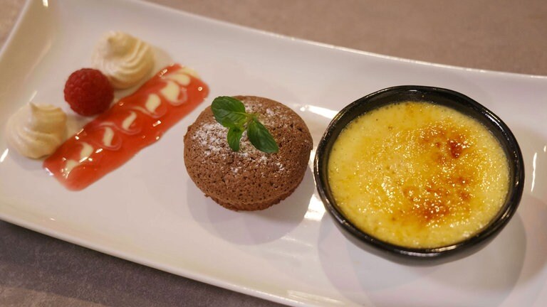 Eierlikör-Crème-Brûlée, Schokoküchlein und Baiser auf einem Spiegel aus ...