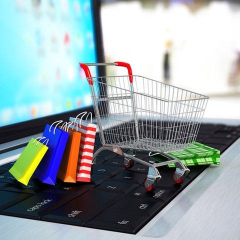 Ein Einkaufswagen und Einkaufstüten stehen auf einer Tastatur eines Laptops. (Foto: Getty Images, Thinkstock -)