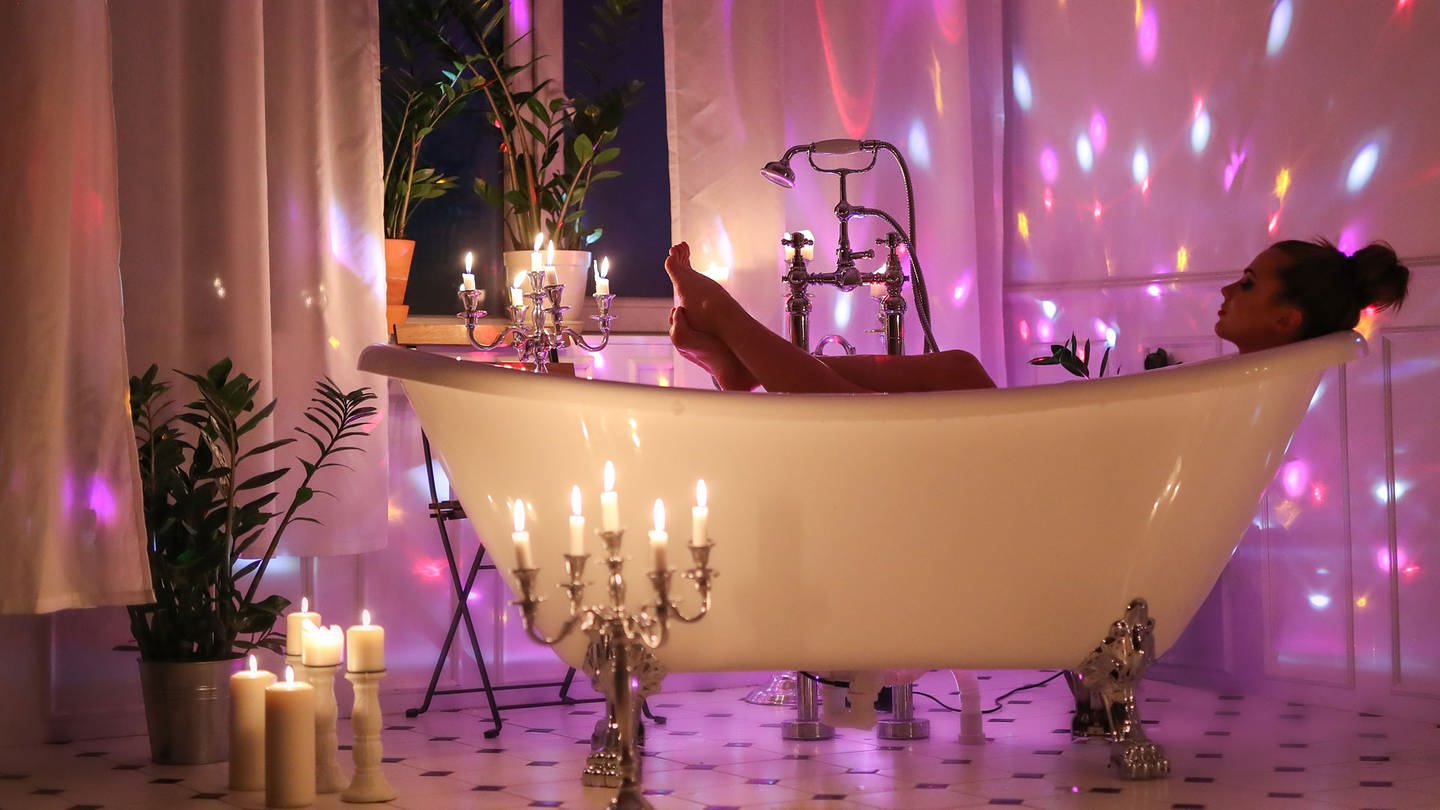 Frau genießt Bad in einem romantisch beleuchteten Badezimmer (Foto: Colourbox)