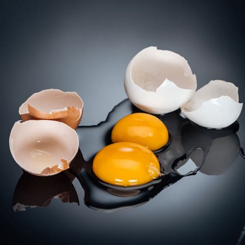 Zwei aufgeschlagene Eier liegen auf einem Tisch. Das Eiweiß ist rund um das Eigelb verteilt, diie Eierschalen liegen daneben. (Foto: Colourbox)