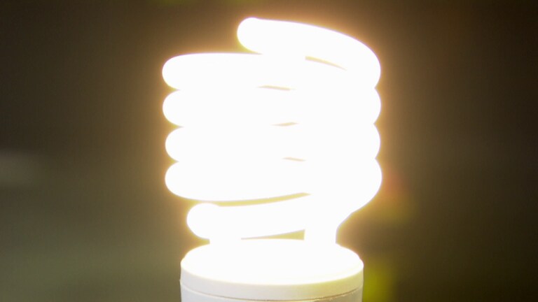 Eine Energiesparlampe leuchtet mit 60 Watt vor einem dunklen Hintergrund. (Foto: SWR)