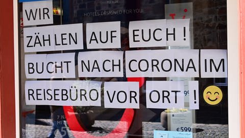 in Reisebüro mit einem rieseigen Schaufenstensterschild auf dem steht: "Wir zählen auf Euch! Bucht nach Corona im Reisebürovor Ort!"  (Foto: dpa Bildfunk, picture alliance/Uwe Zucchi/dpa)