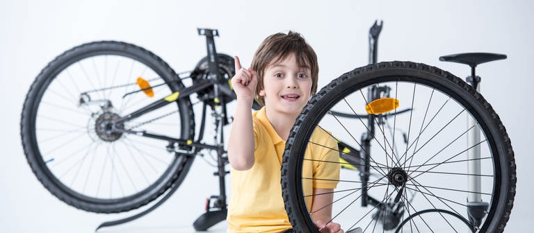 Kind beim Wechseln und Flicken eines platten Fahrradreifens (Foto: Colourbox)