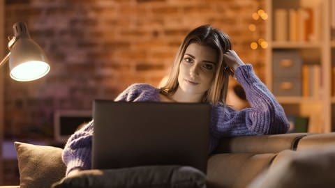 Junge Frau auf Sofa sieht sich Film auf dem Laptop an. Wie klimaschädlich sind Internet-Videos? (Foto: Colourbox)