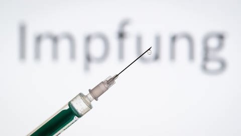 Eine Spritze wird vor den Schriftzug «Impfung» gehalten (Foto: dpa Bildfunk, Picture Alliance)