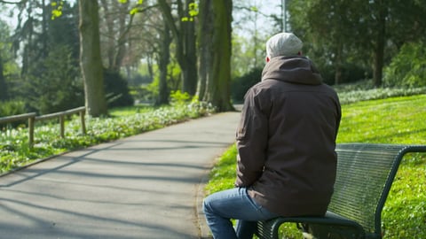Ein Mann sitzt mit dem Rücken zur Kamera auf einer Bank in einem Park.  (Foto: SWR)