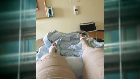 Eine Person liegt mit vollständig verbundenen Beinen in einem Krankenbett. (Foto: SWR)