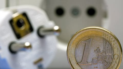 Eine Ein-Euro-Münze neben einer Steckdose und einem Stecker (Foto: dpa Bildfunk, Picture Alliance)