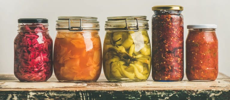 Fünf Einmachgläser mit fermentierten Lebensmitteln stehen auf einem Holztisch. (Foto: Colourbox, COLOURBOX28994884)
