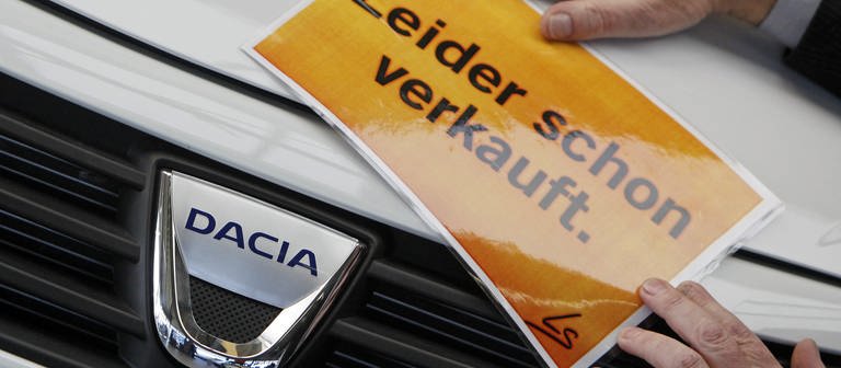 in Verkäufer in einem Autohaus in Leipzig befestigt ein Schild "Leider schon verkauft" an einem Dacia Sandero, aufgenommen am Donnerstag (05.02.2009).  (Foto: dpa Bildfunk, picture-alliance/ dpa | Jan Woitas)