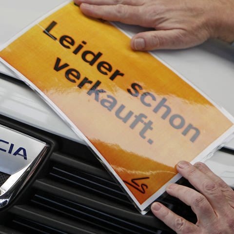 in Verkäufer in einem Autohaus in Leipzig befestigt ein Schild "Leider schon verkauft" an einem Dacia Sandero, aufgenommen am Donnerstag (05.02.2009).  (Foto: dpa Bildfunk, picture-alliance/ dpa | Jan Woitas)