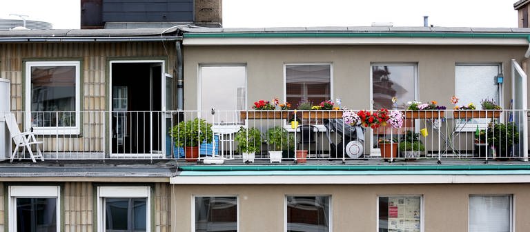 Bunte Blumen blühen vor grauer Fassade auf einem Balkon. (Foto: dpa Bildfunk, picture alliance / dpa | Rolf Vennenbernd)