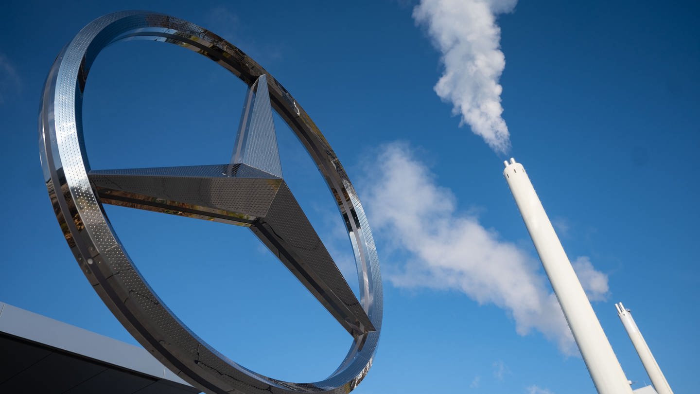 Ein überdimensionaler Mercedes-Stern steht vor dem Kundenzentrum des Mercedes-Benz Werks Sindelfingen. Im Hintergrund ist ein rauchender Schornstein zu sehen. (Foto: dpa Bildfunk, picture alliance/dpa | Marijan Murat)