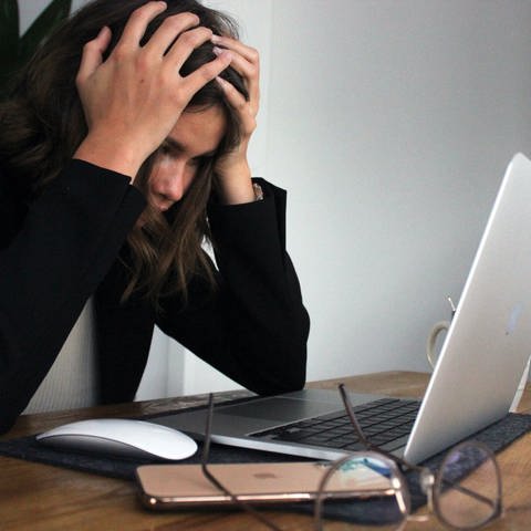 Frau sitzt verzweifelt mit über den Kopf geschlagenenen Händen an ihrem Laptop und surft im Internet. (Foto: Colourbox, Colourbox | Elisa Ventur)