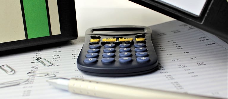 Taschenrechner liegt auf Unterlagen. Die Neuberechnung der Grundsteuer ist verpflichtend für Eigentümer. (Foto: Colourbox)
