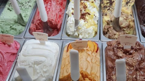 Leckeres Speise-Eis zu den Eisheiligen: Verschiedene Eissorten in den üblichen Metallbehältern in einer Eisdiele. (Foto: Unsplash/Lama Roscu )