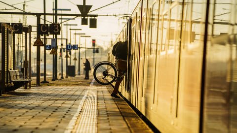 Ein Bahnreisender hebt sein Fahrrad in eine S-Bahn. (Foto: dpa Bildfunk, Picture Alliance)