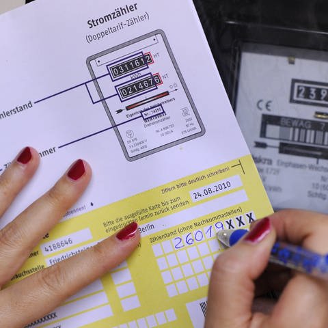 Person mit lackierten Fingernägeln schreibt den Stand eines Stromzählers in das dafür vorgesehen Formular. (Foto: dpa Bildfunk, Picture Alliance)