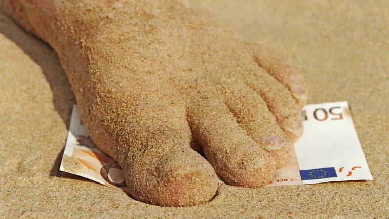 Fuß steht im Sand auf einen 50-Euroschein (Foto: Colourbox)