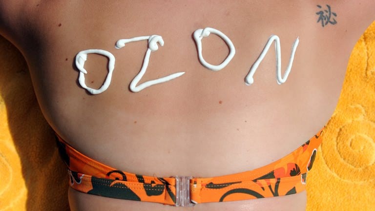 Eine junge Frau hat den Schriftzug "Ozon" aus Sonnencreme auf ihrem Rücken stehen.  (Foto: dpa Bildfunk, picture alliance / dpa /Caroline Seidel)