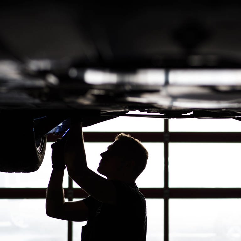 Mechaniker arbeitet in einer KfZ-Werkstatt an der Unterseite eines Autos (Foto: dpa Bildfunk, Foto: David-Wolfgang Ebener/dpa)