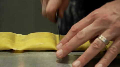 Eine Person schneidete mit einem Messer mehrere selbstgemachte Maultaschen auseinander