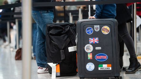Famile am Flughafen mit Koffer, auf dem UK-Flagge zu sehen ist. (Foto: dpa Bildfunk, Picture Alliance)