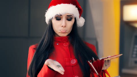 Spenden in der Weihnachtszeit: Ratlose Frau mit Nikolausmütze, Bargeld und Portemonnaie (Foto: Colourbox)